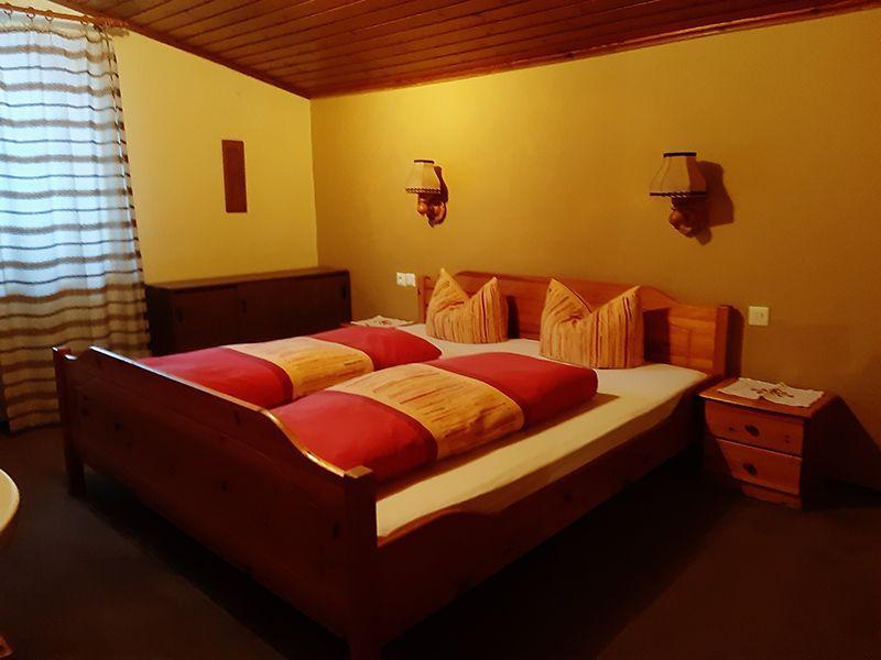 Schlafzimmer mit Doppelbett aus Holz in Appartement 4 der Pension Obladis
