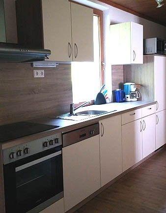 Wohnküche mit heller Front und Mikrowelle in Appartement 6