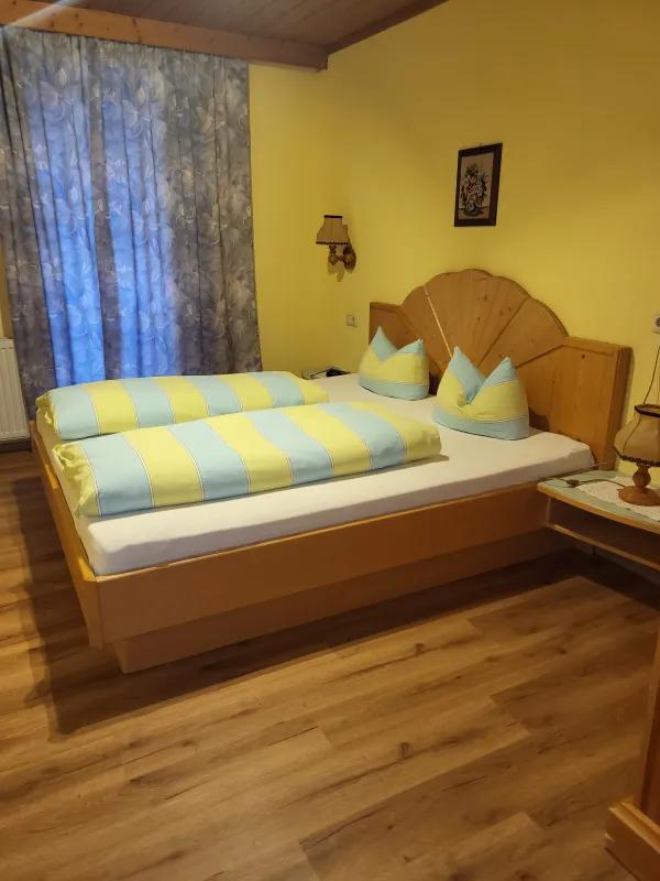 Schlafzimmer mit Doppelbett und Fächer-Betthaupt aus Holz in Appartement 6 der Pension Obladis