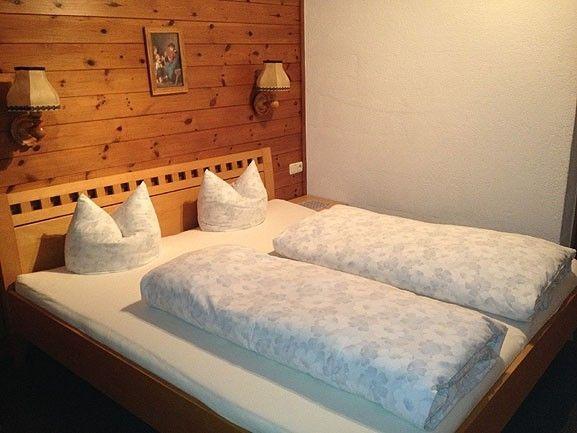 Zweites Schlafzimmer mit Holzwand und hellem Doppelbett in Appartement 7