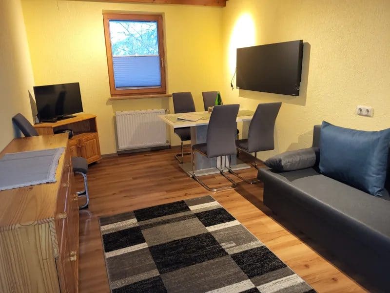 Wohnraum einer Ferienwohnung im s’Obladis mit Sofa, Essplatz und Flachbild-TV