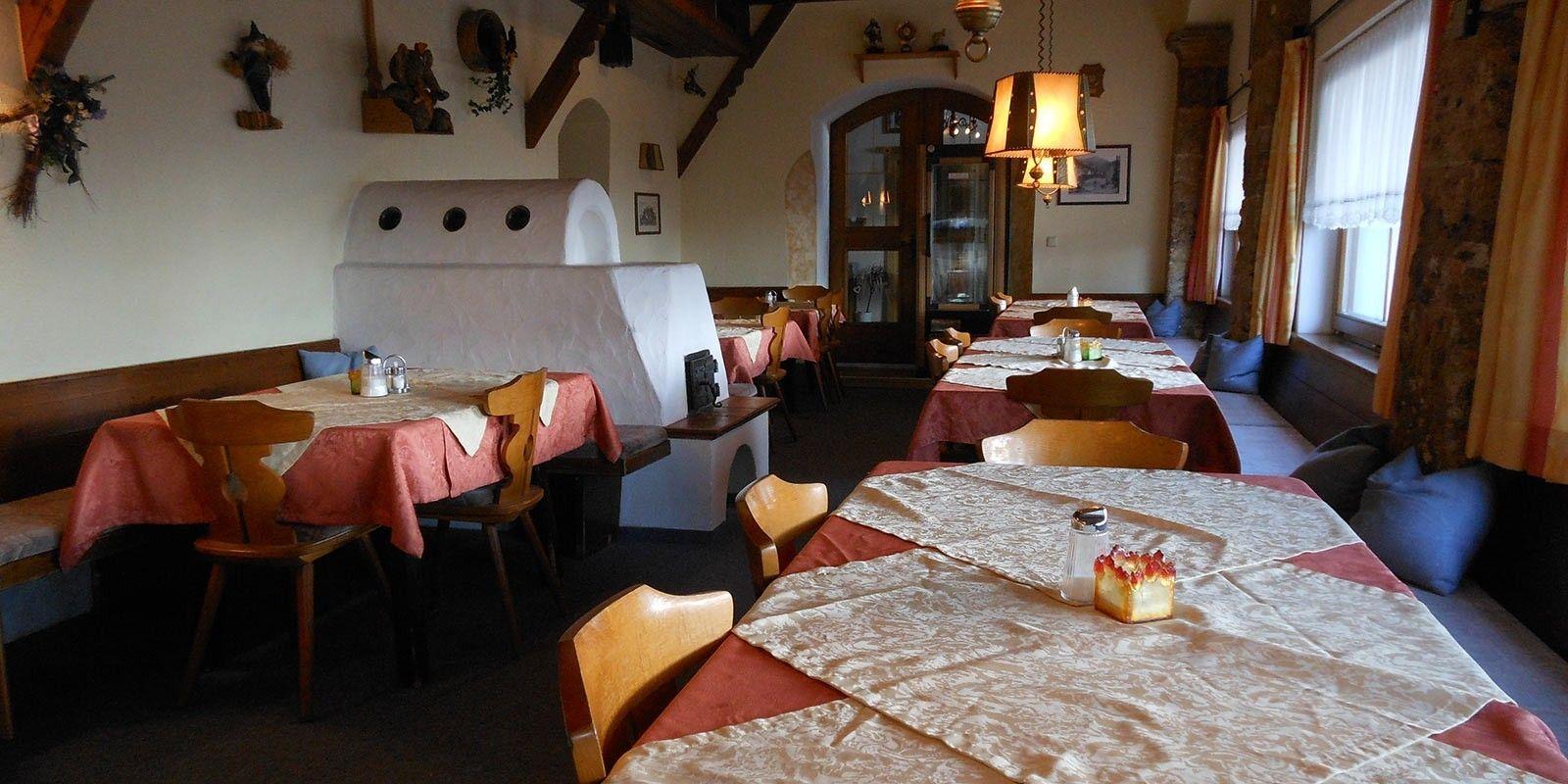 Gemütliche Panoramastube im Café Obladis mit gedeckten Tischen, Kachelofen und Bergblick durch die Fenster