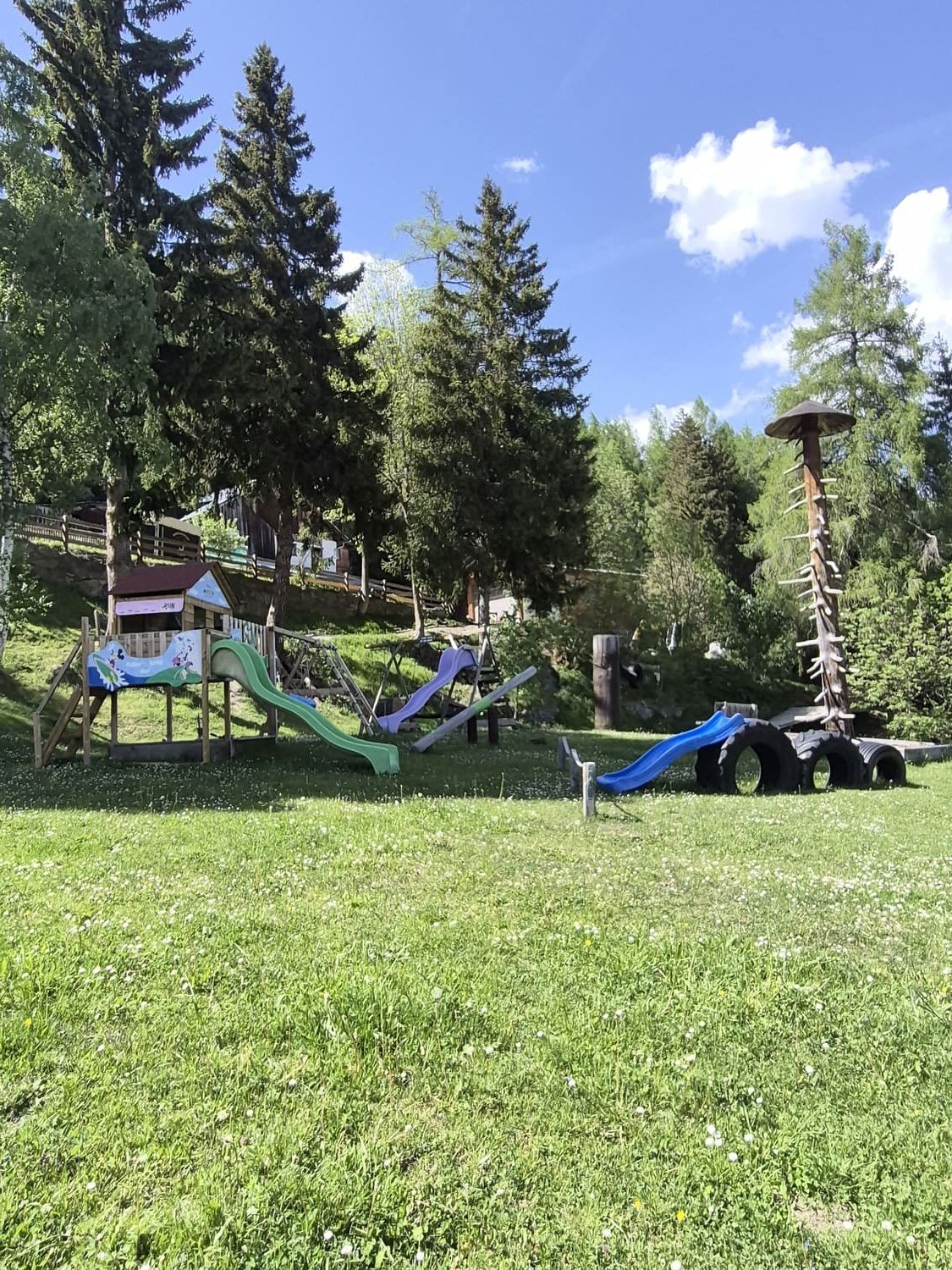 Abenteuerspielplatz der Pension Obladis mit Rutschen, Reifen-Parcours und Spielhaus am Waldrand