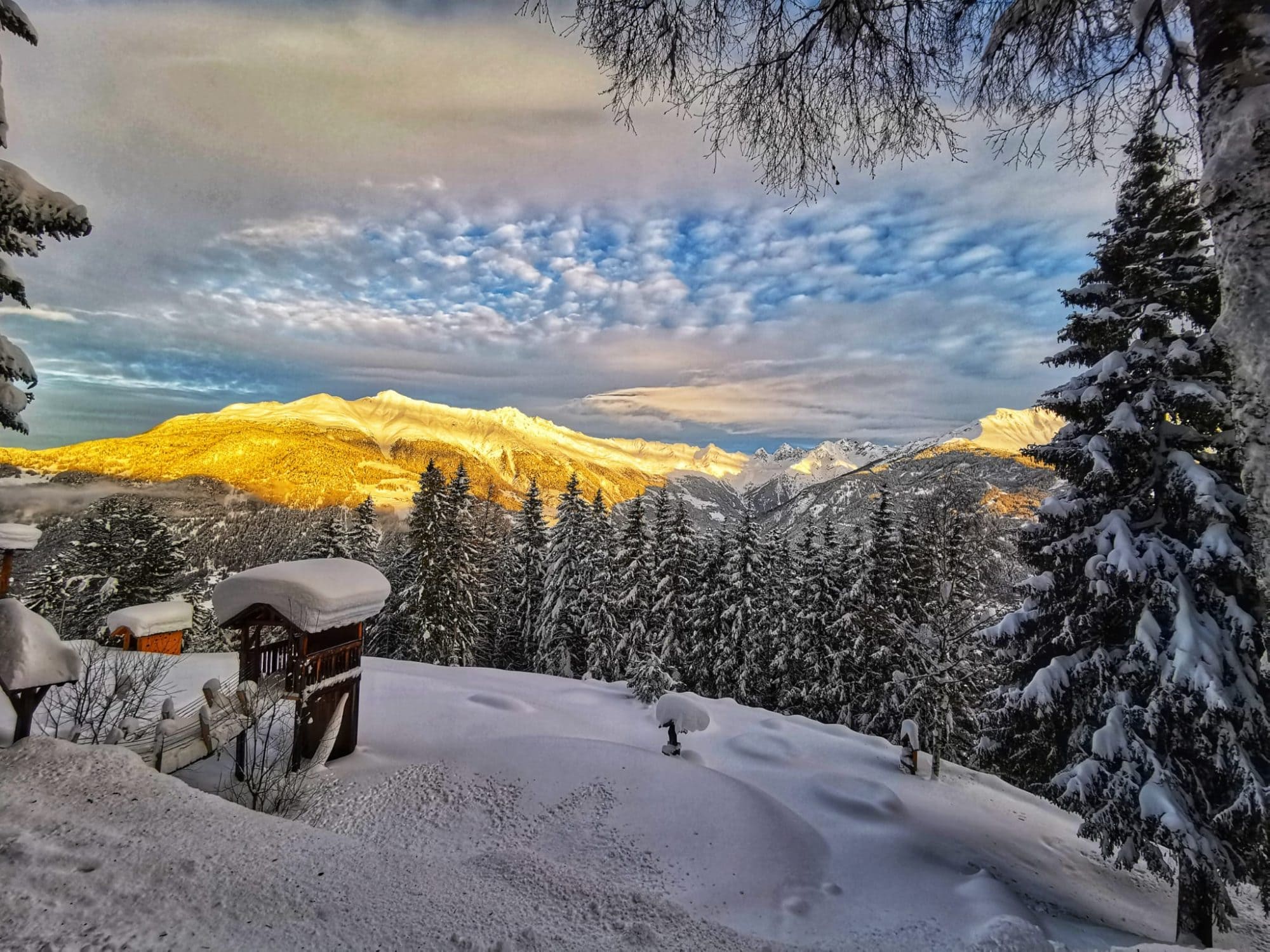 Verschneites Winterpanorama am Morgen mit frischem Neuschnee und Alpenglühen auf den Gipfeln